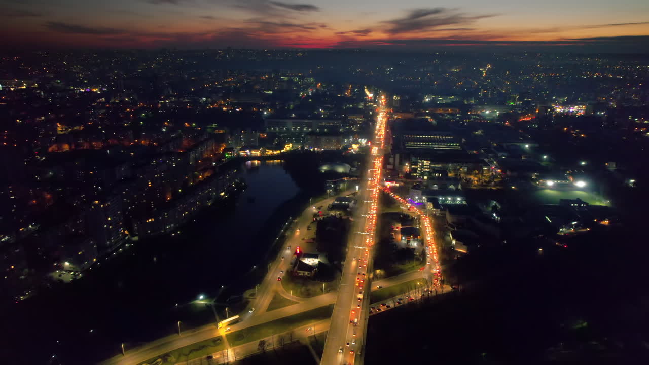 Aerial drone view of Chisinau at sunset, Moldova. View of the city with multiple buildings, lake, roads with traffic, illumination