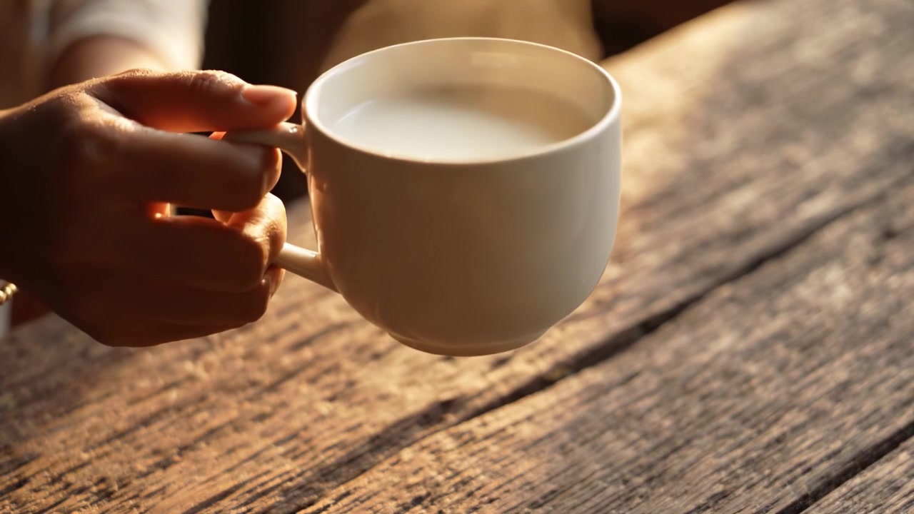Un momento accogliente: gustare una tazza di latte caldo su un tavolo di legno rustico, catturando l'essenza di comfort e serenità in un ambiente tranquillo
