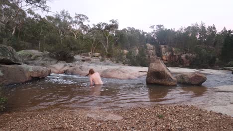 un hombre australiano se acuesta en una piscina de montaña helada cerca de una cascada en medio del invierno en el bosque australiano