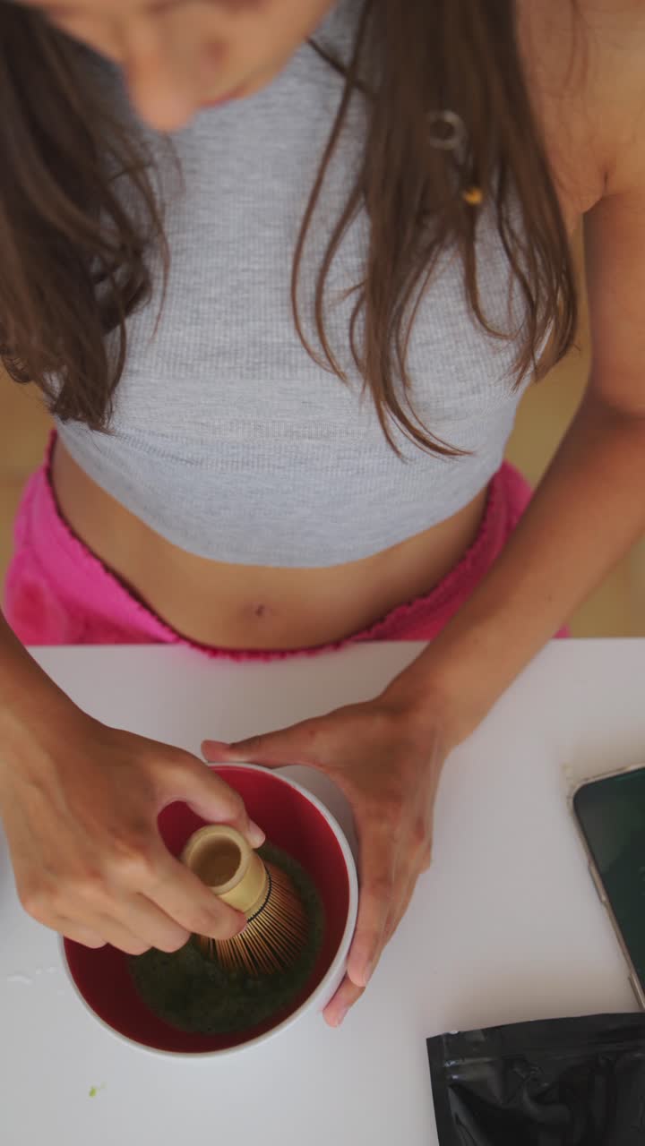 Una persona che sbatte il tè matcha in una ciotola