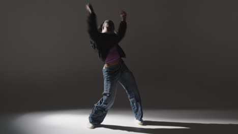 Retrato-De-Estudio-De-Longitud-Completa-De-Una-Mujer-Joven-Bailando-Con-Iluminación-Baja-Sobre-Fondo-Gris-5