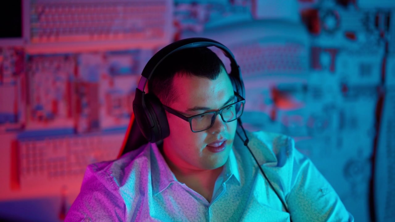 Ung mand med hovedtelefoner og briller taler, mens han gamer