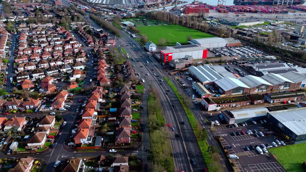 Korkealta kuvattu ilmakuva dronella Southamptonin Millbrookin esikaupunkialueen asuinalueesta auringonlaskun aikaan, jota ympäröivät puut, kodit ja luonto. Kuvattu talvella liikenteen ja autojen ajaessa kaduilla.