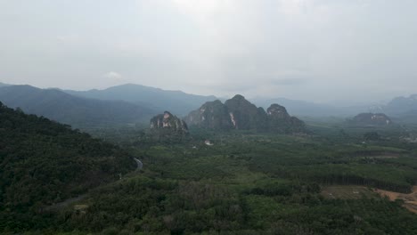 aerial view of lush green forests and towering limestone karsts in a tropical landscape