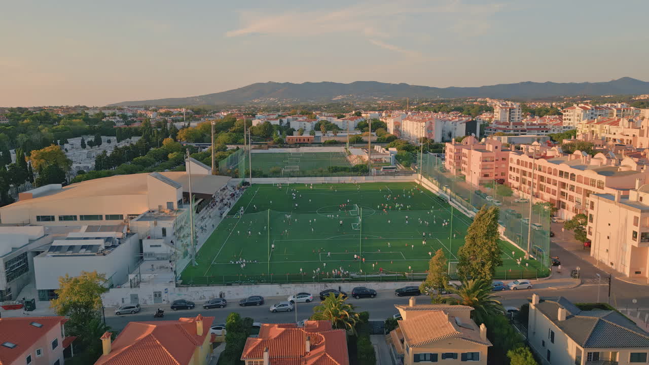 Drone small town stadium under evening sunlight. football green field
