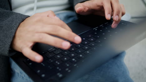los dedos de freelance enviando mensajes de texto en el teclado de la computadora portátil fuera de primer plano.