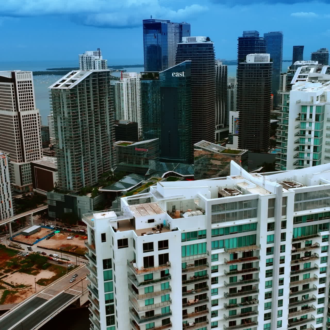 Descending above the high-rise buildings in Miami, Florida, USA. Waterscape under dark blue sky at backdrop.