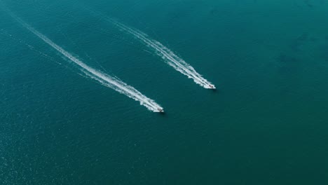 aerial view down shot, two jets skied racing with each other on the blue sea on a sunny day in san juanico, california sur, mexico