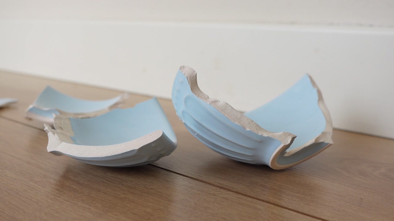 Broken Light Blue Ceramic Pot Pieces on a Wooden Floor