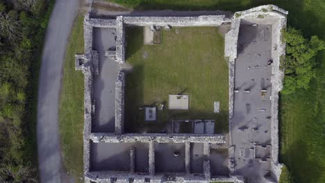 Ascending-aerial-reveals-compartments-of-Annaghdown-Abbey-ruins,-Galway