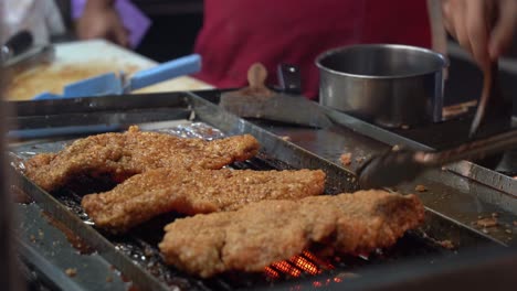 Appetizing-honey-soy-coated-delicious-fried-chicken-fillet-grilling-on-hot-grill,-professional-chef-brush-tasty-sauce-on-the-meat-with-aromatic-smell-at-famous-night-market,-Taiwan,-Asia