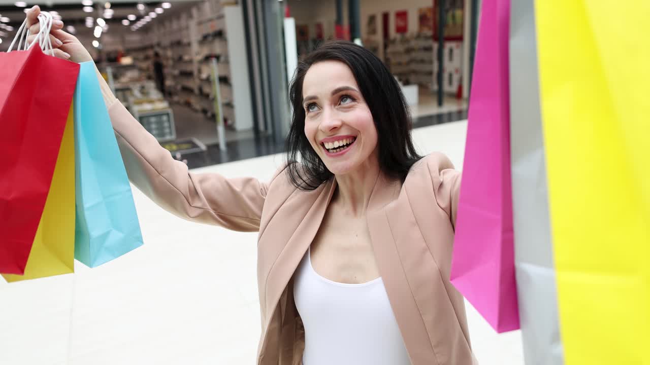 Giovane donna felice che raccoglie borse della spesa colorate, filmato 4k