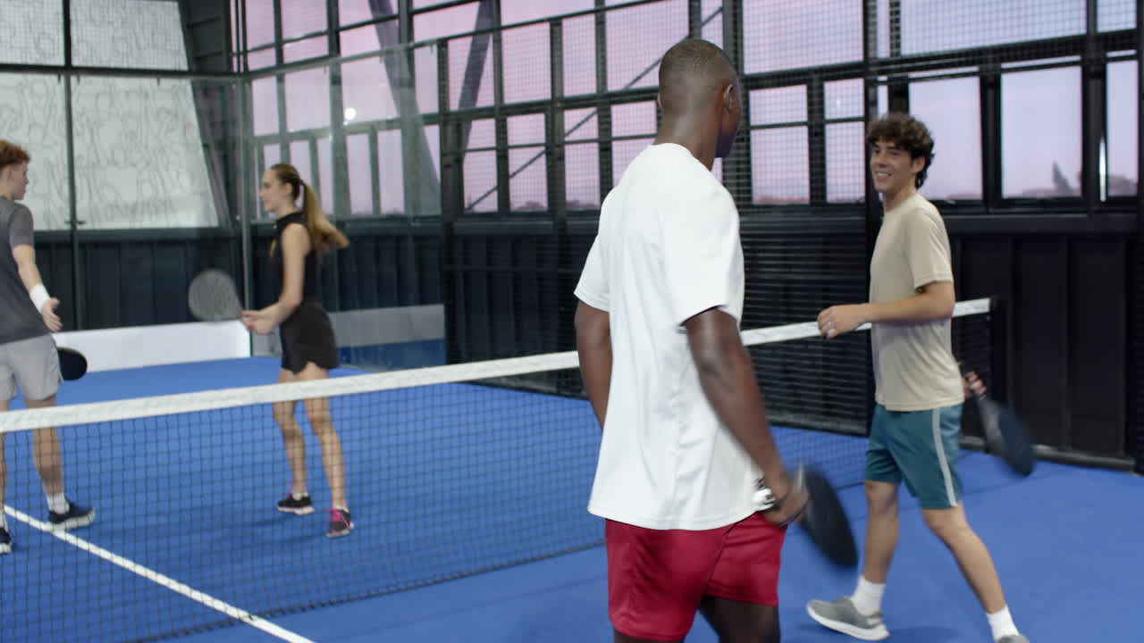 Young man playing padel tennis on blue indoor court, focusing on game
