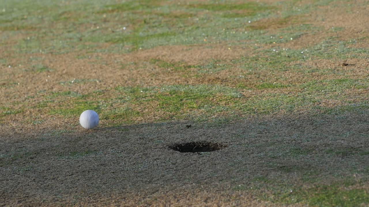 홀을 지나서 그린 롤에 퍼팅된 골프공, 낮고 느린 동작