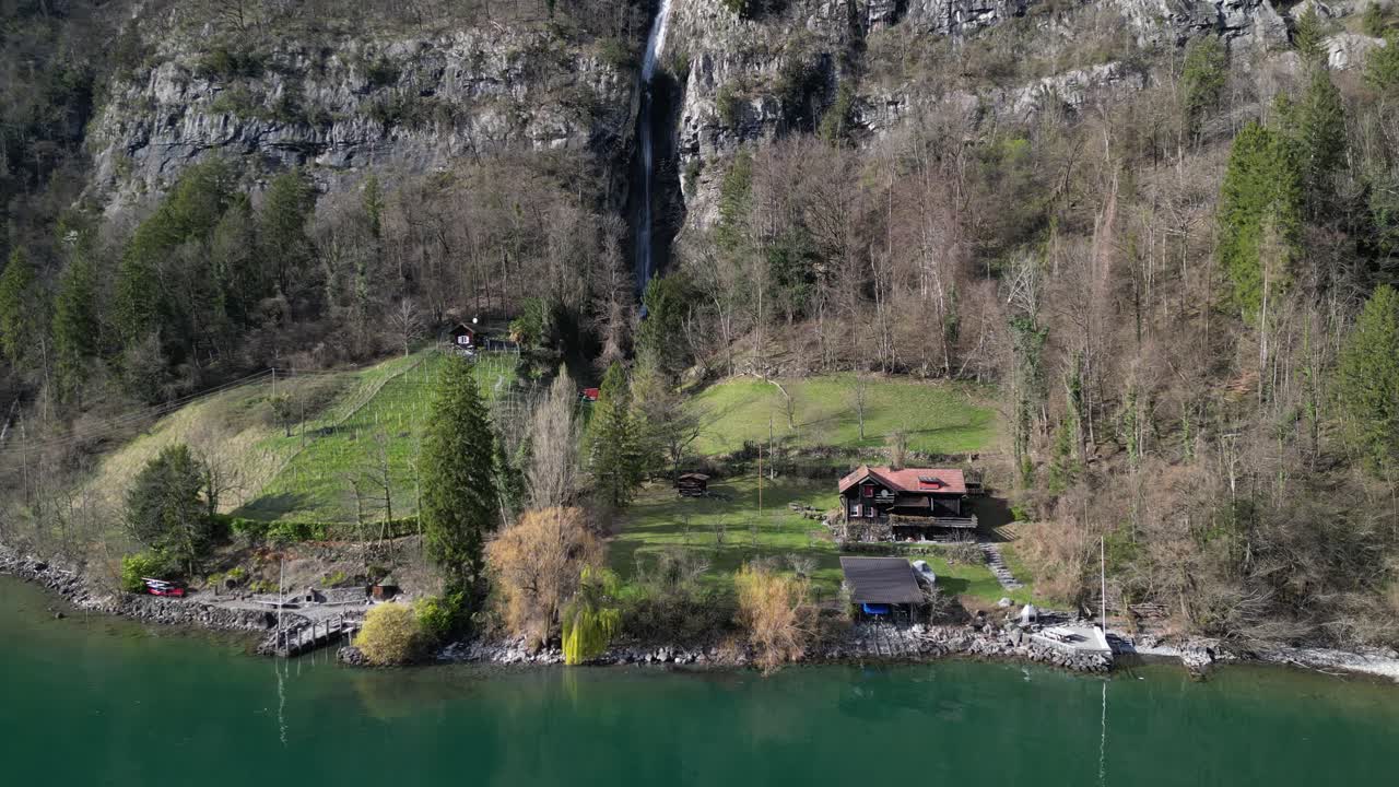Ripresa panoramica con drone che mostra una capanna di legno sulla riva di un lago tranquillo, nelle Alpi svizzere.