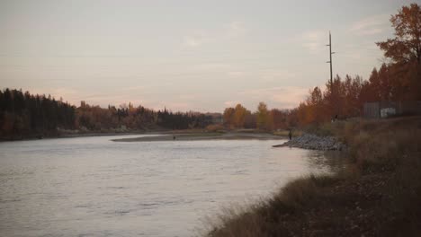 Weite-Aufnahme-Eines-Ruhigen-Bow-River,-Umgeben-Von-Herbstbäumen-Mit-Lebendigem-Laub