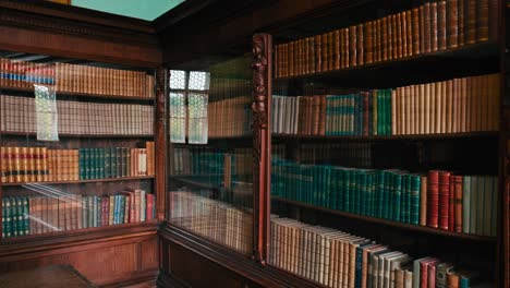 Vast collection of books in an elaborately carved bookcase by stained glass in Trakošćan Castle, Croatia