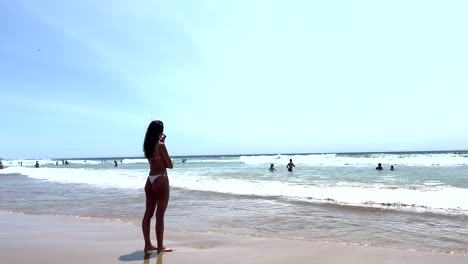 woman with white bikini pensive on the beach looking at the sea in caparica beach