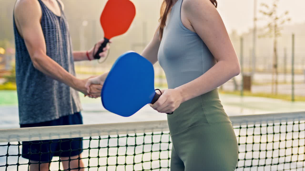 Hombre y mujer haciendo un apretón de manos secreto después de jugar al pickleball tras la lluvia