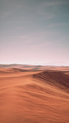 un impresionante paisaje desértico con dunas de arena rodantes bajo un vibrante cielo de puesta de sol