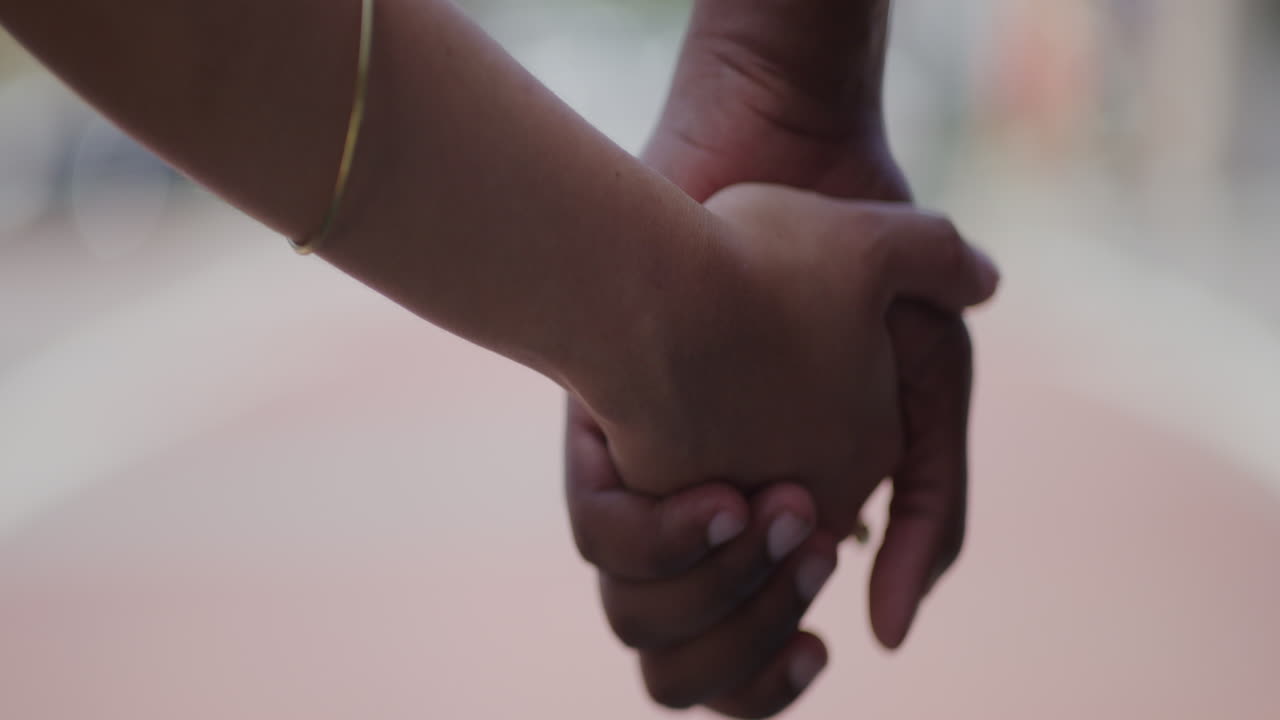 Young Diverse Couple Hold Hands Gently in Slow Motion, Close Up