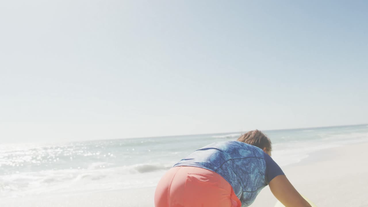 행복한 시니어 아프리카계 미국인 여성이  ⁇ 니 비치에서 서핑 보드를 들고 있습니다.