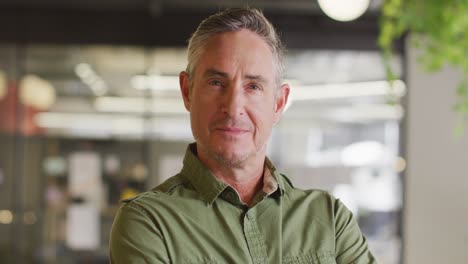 Portrait-of-happy-caucasian-businessman-looking-at-camera-at-office