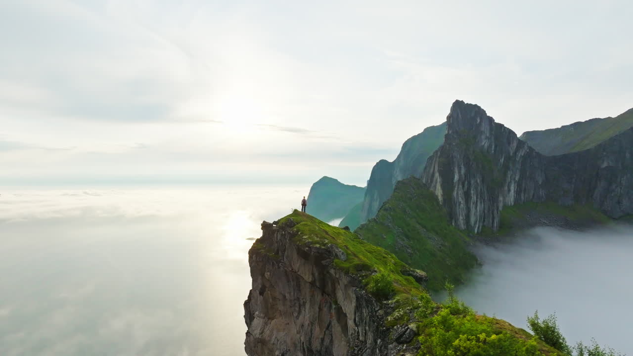 Hiker on narrow arctic Senja Hesten mountain ridge with spectacular view; drone