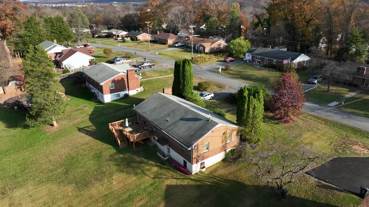 Orbiting drone flight over a quiet American suburban neighborhood in fall, with homes, vibrant trees and streets under clear sunlight, hinting at digital connectivity and sustainable energy themes