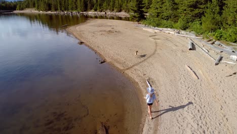 Woman-with-her-pet-dog-walking-near-river-coast-on-a-sunny-day-4k