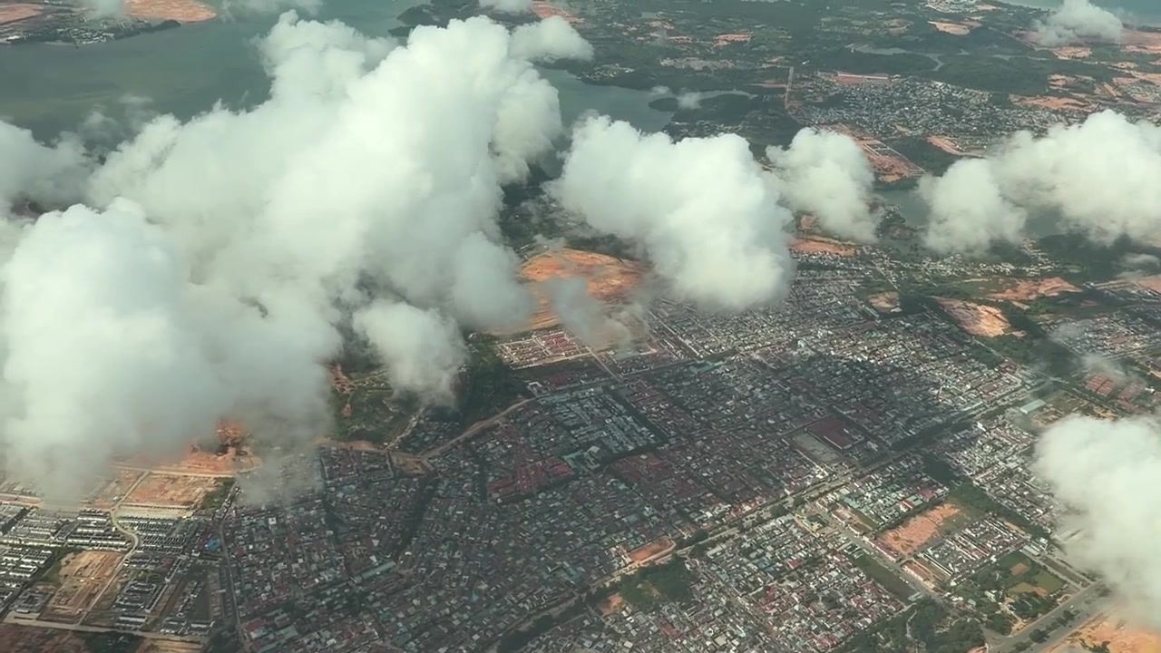 Aereo che vola sopra le nuvole e una vista aerea di Batam.