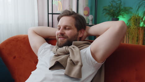 tired young man lying down on comfortable couch, taking a rest, daytime nap relaxing falling asleep