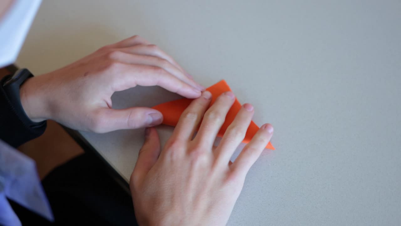 mujer caucásica blanca habilidosa haciendo un zorro de origami, mujer juega con la famosa carpeta de papel arte tradicional japonés