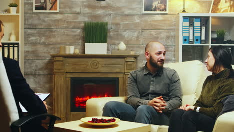 young couple hug each other sitting on couch at therapy