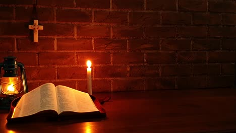 open bible on table with candle and oil lamp background