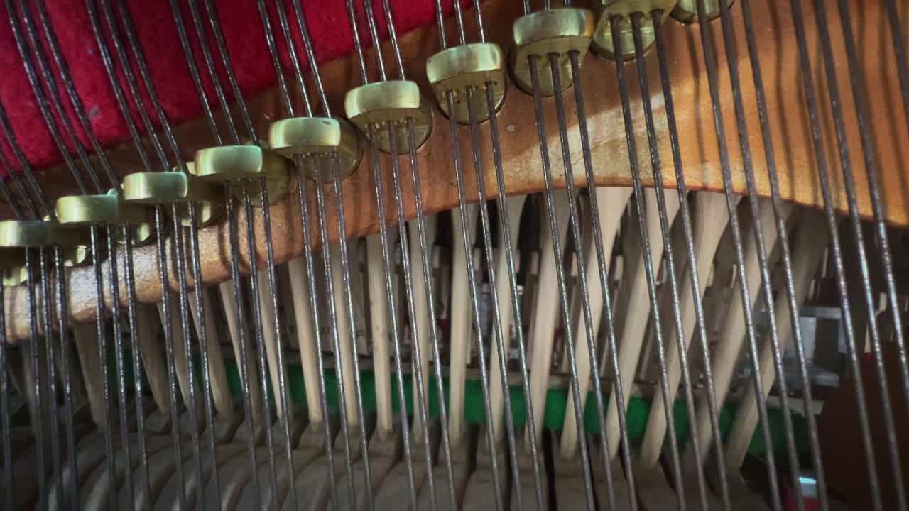 Macro-style close-up of piano hammers hitting the strings in sequence inside an upright piano, showing the complex wooden and felt mechanism in action