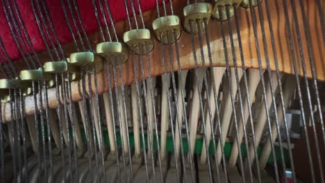 macro-style close-up of piano hammers hitting the strings in sequence inside an upright piano, showing the complex wooden and felt mechanism in action
