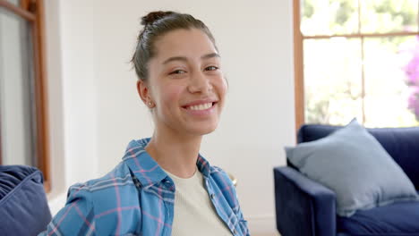 Portrait-of-happy-biracial-teenage-girl-standing-in-sunny-room-at-home,-copy-space,-slow-motion