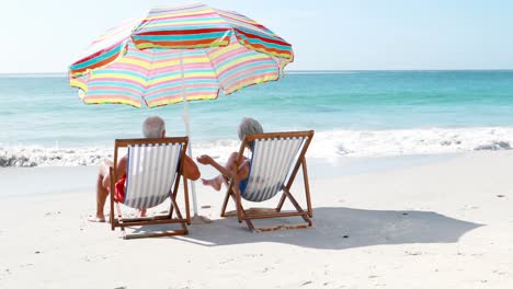 Retired-old-couple-lying-on-deckchair-while-drinking-cocktails