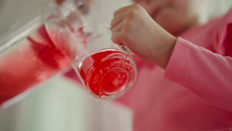 child pouring a red drink