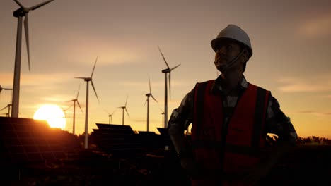 engineer at a wind and solar farm at sunset