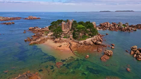 receding drone shot reveals château de costaérès on a granite islet off trégastel, surrounded by sea and rugged rocks