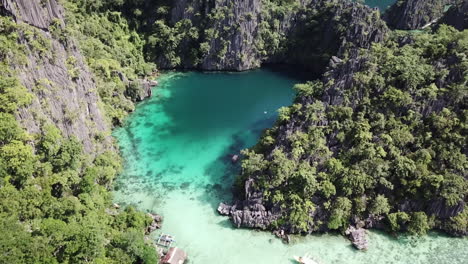 Amazing cliffs of gray rocks covered by green plants with clear turquoise sea on a bright summer day . Drone backwards dolly shot