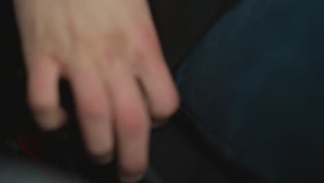 close up of car owner hand locking seat belt in vehicle cabin beside fogged window wearing winter jacket focusing on finger pressing buckle latch amid ambient lighting highlighting safety gesture
