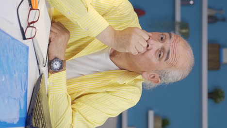 Vertical-video-of-Home-office-worker-old-man-thinking-looking-at-camera.