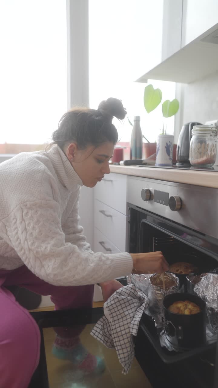 Mujer revisando productos horneados en el horno.