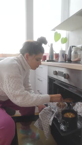 woman checking on baked goods in oven