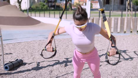 woman doing trx workout in a park