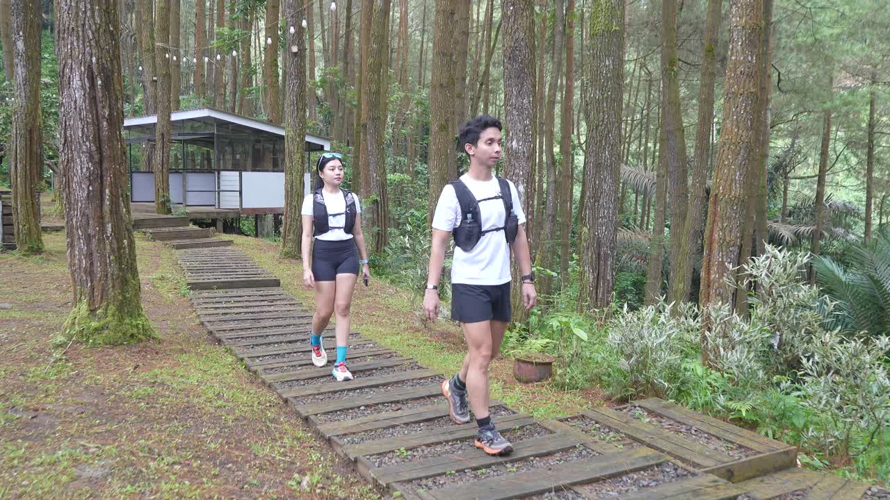 Asian couple walking on forest trail path during outdoor adventure in Indonesia