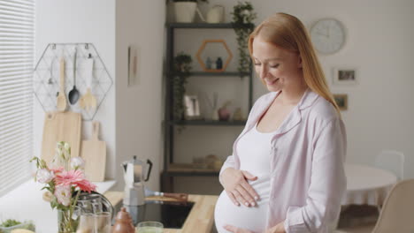 mujer embarazada feliz en la cocina